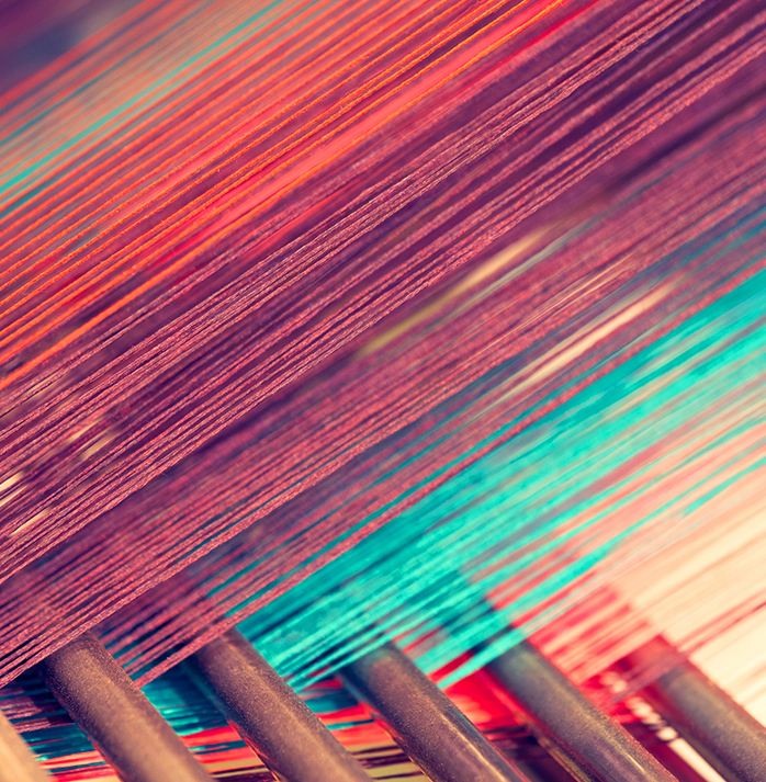 Close-up of colorful threads on a loom in a fabric mill, highlighting intricate weaving patterns